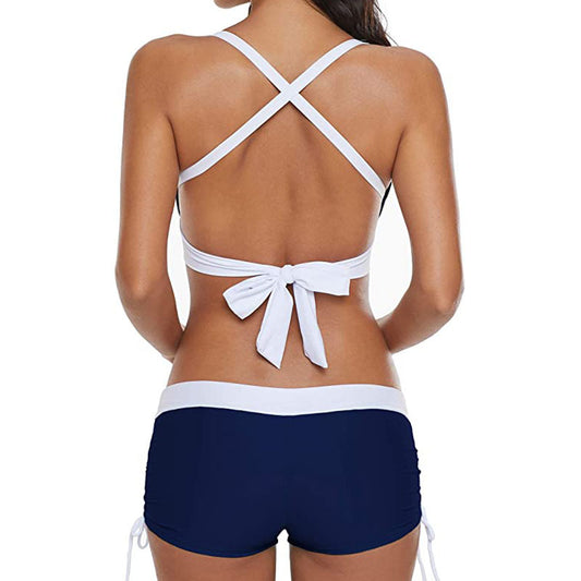 White bikini top with criss-cross straps and navy shorts on a white background