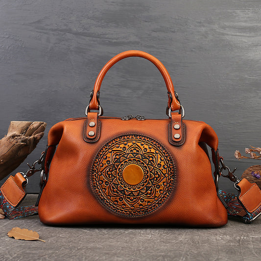 Brown leather handbag with intricate design on a gray background