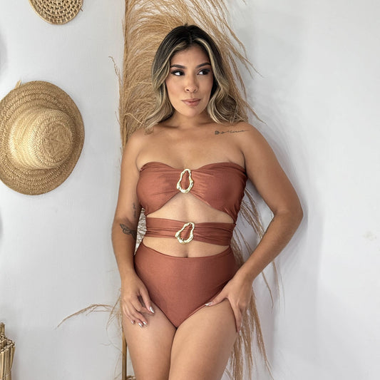 Woman wearing a brown swimsuit with decorative elements against a neutral background