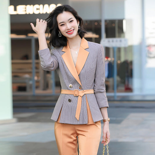 Woman in a gray and orange suit standing outdoors with a blurred background