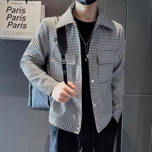Person wearing a black and white checkered jacket against a gray wall.