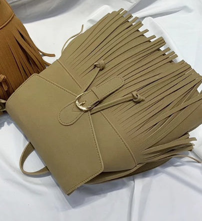 Beige handbag with fringe details on a white background