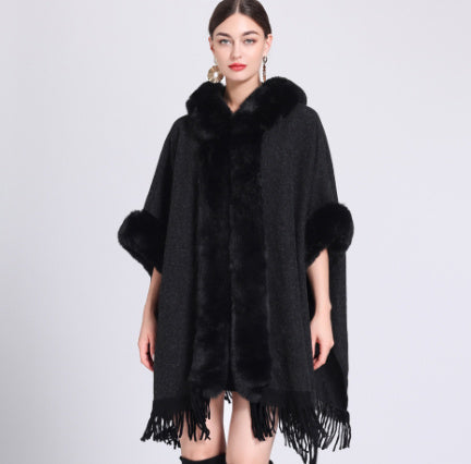 Black poncho with fur trim worn by a model on a white background