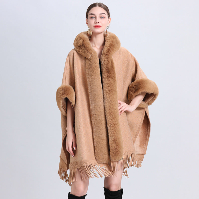 Woman wearing a brown poncho with fur trim on a light gray background