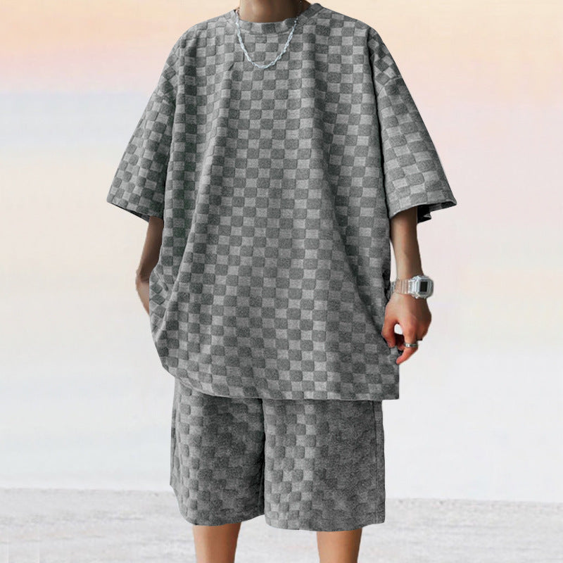 Person wearing a gray checkered outfit on a light background