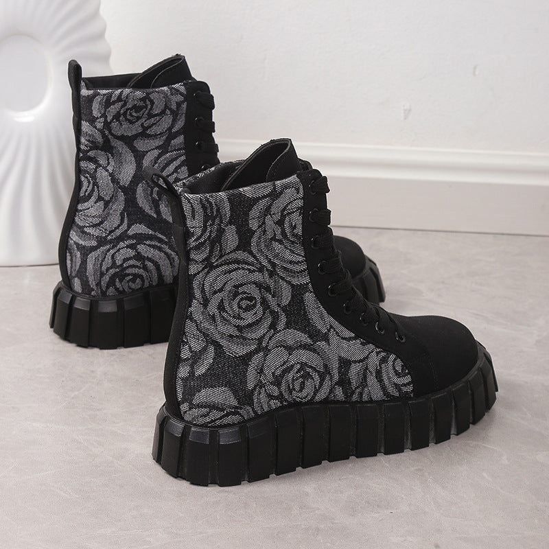 Black and gray floral patterned boots on a light gray surface with a white textured background