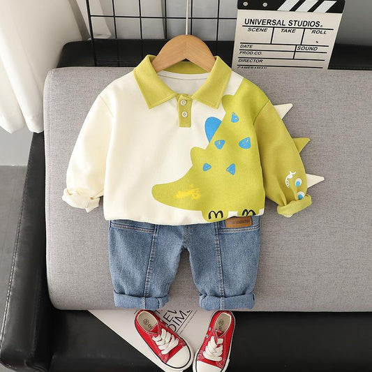 Children's outfit with dinosaur-themed shirt and jeans on a gray couch.