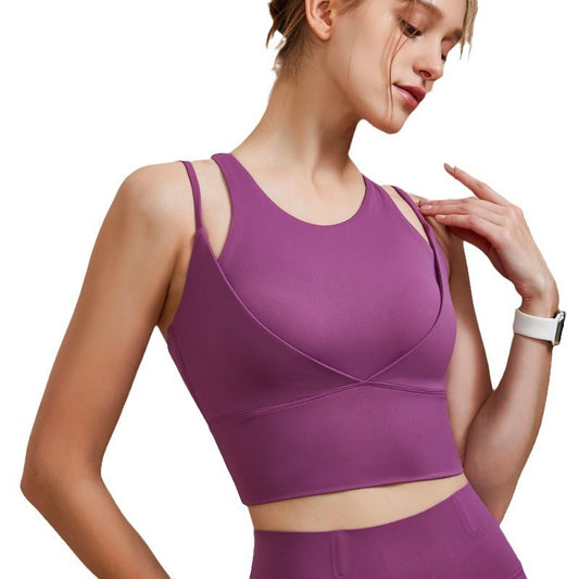 Woman wearing a purple sports bra and leggings on a white background