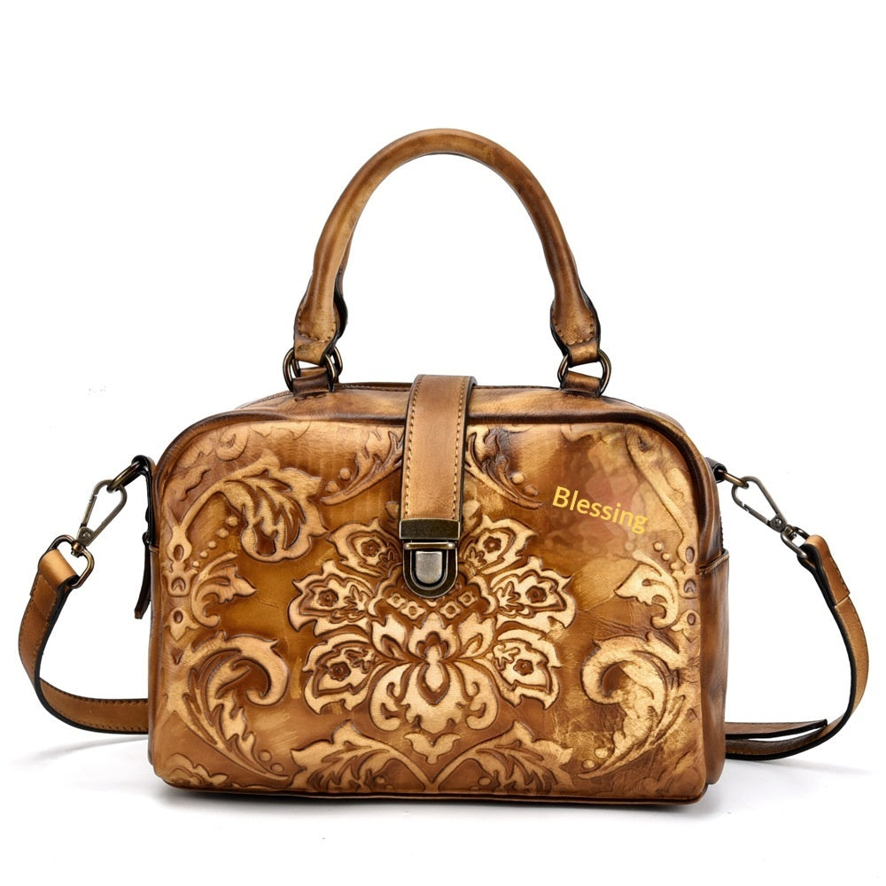 Brown leather handbag with floral patterns and 'Blessing' text on a white background