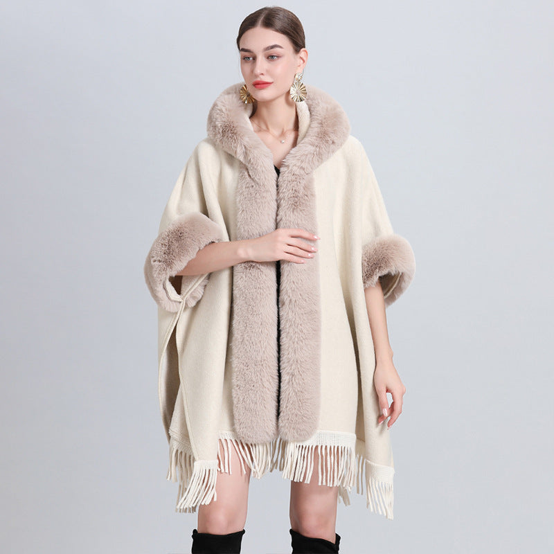 Woman wearing a cream-colored poncho with fur trim on a light gray background
