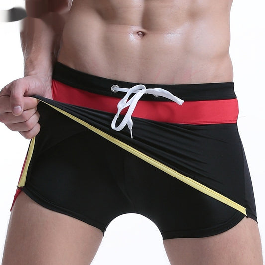 Black swim shorts with red waistband and yellow stripe held by a person on a white background