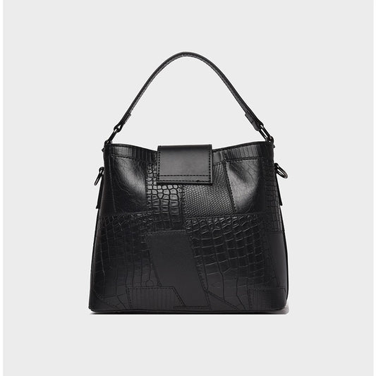 Black handbag with crocodile texture on a light gray background