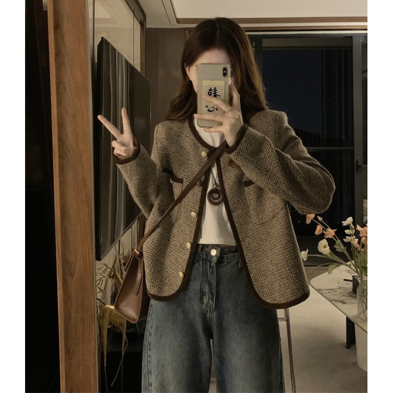 Person wearing a brown blazer taking a mirror selfie indoors.
