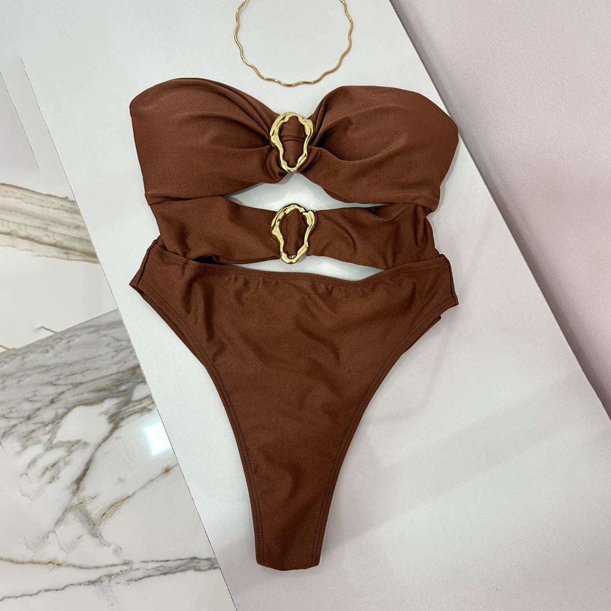 Brown bikini set with gold accents on a white surface