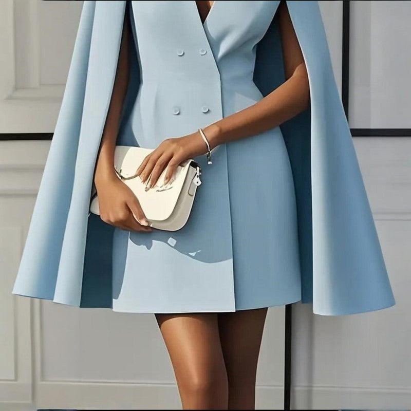 Person wearing a light blue coat and holding a white handbag against a neutral background