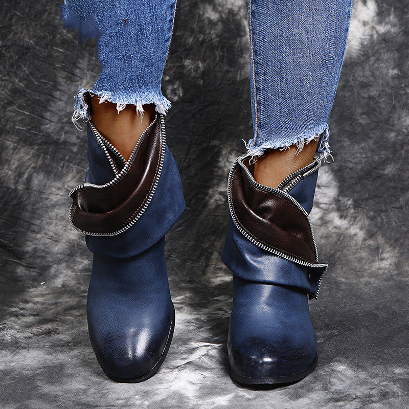 Blue ankle boots with brown lining worn with ripped jeans on a textured gray background