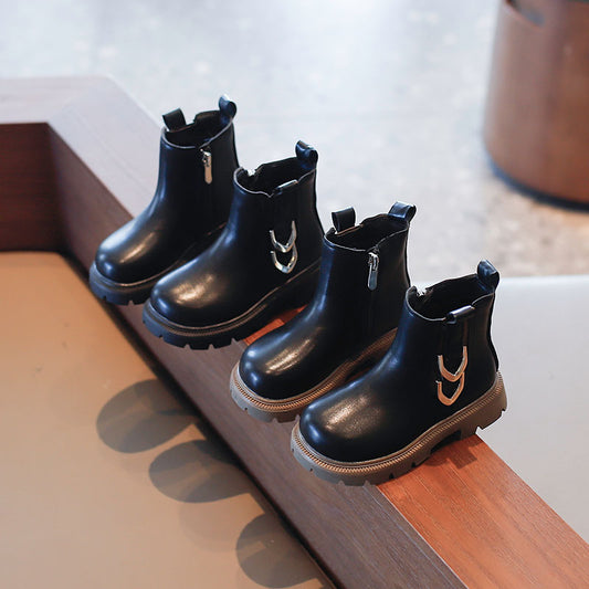 Four black boots with gold accents arranged on a wooden surface.