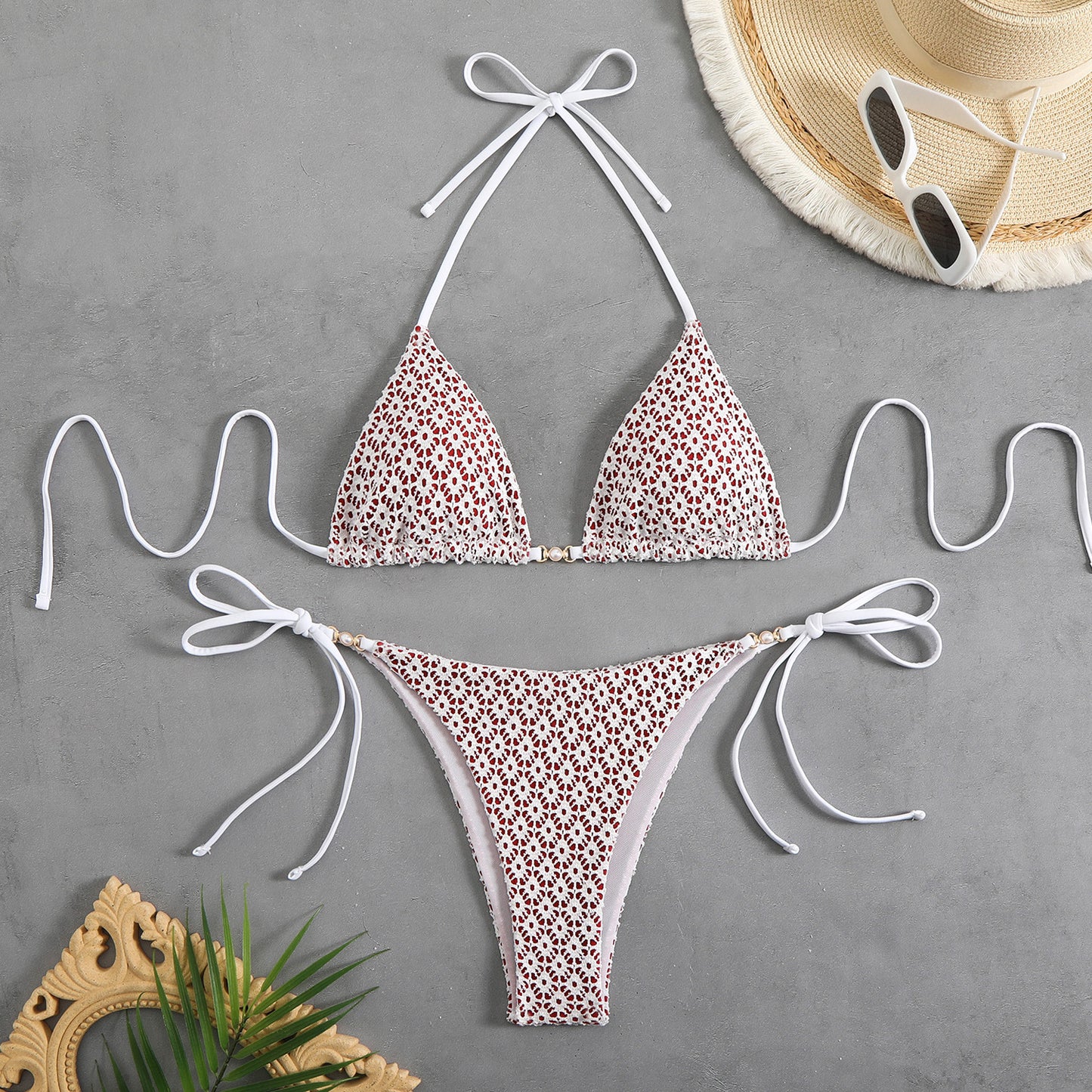Leopard print bikini set with white straps on a gray surface, accompanied by a hat and sunglasses.