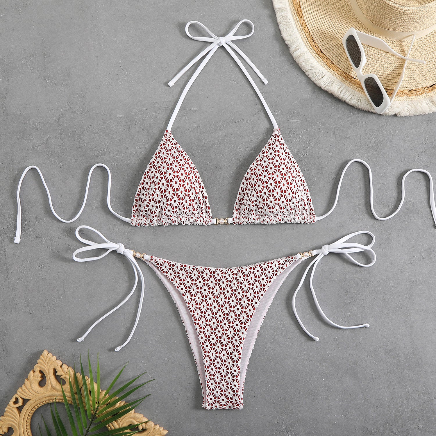 Leopard print bikini set with white straps on a gray surface, accompanied by a hat and sunglasses.