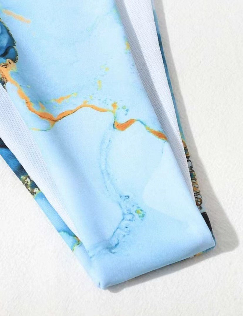 Blue fabric with gold and green abstract patterns on a white background