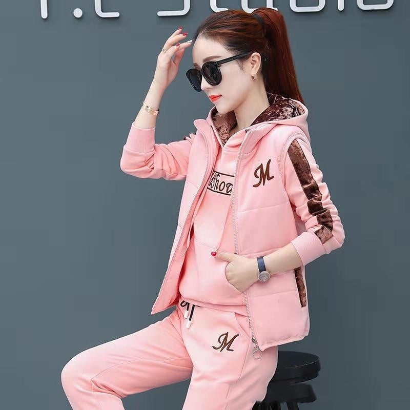 Woman wearing a pink tracksuit with 'M' logo on a dark background