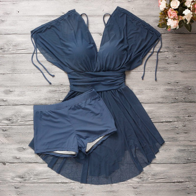 Blue swimsuit on a wooden surface with flowers in the corner