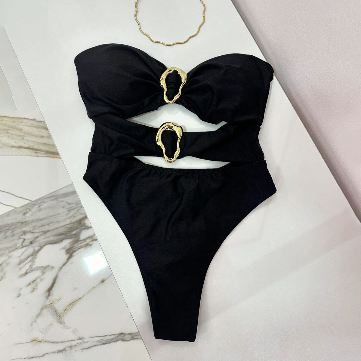 Black bikini with gold accents on a marble surface
