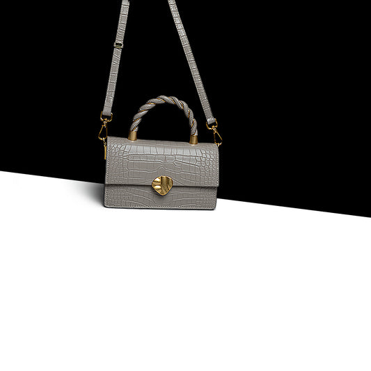 Gray handbag with a heart-shaped clasp on a black and white background