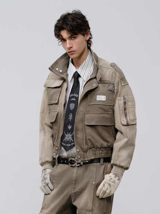 Man wearing a beige jacket, white shirt, and tie with a gray background