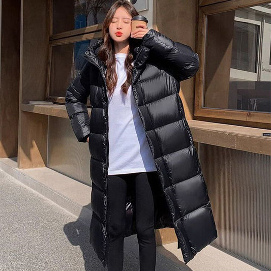 Person wearing a long black puffer coat taking a selfie outdoors.