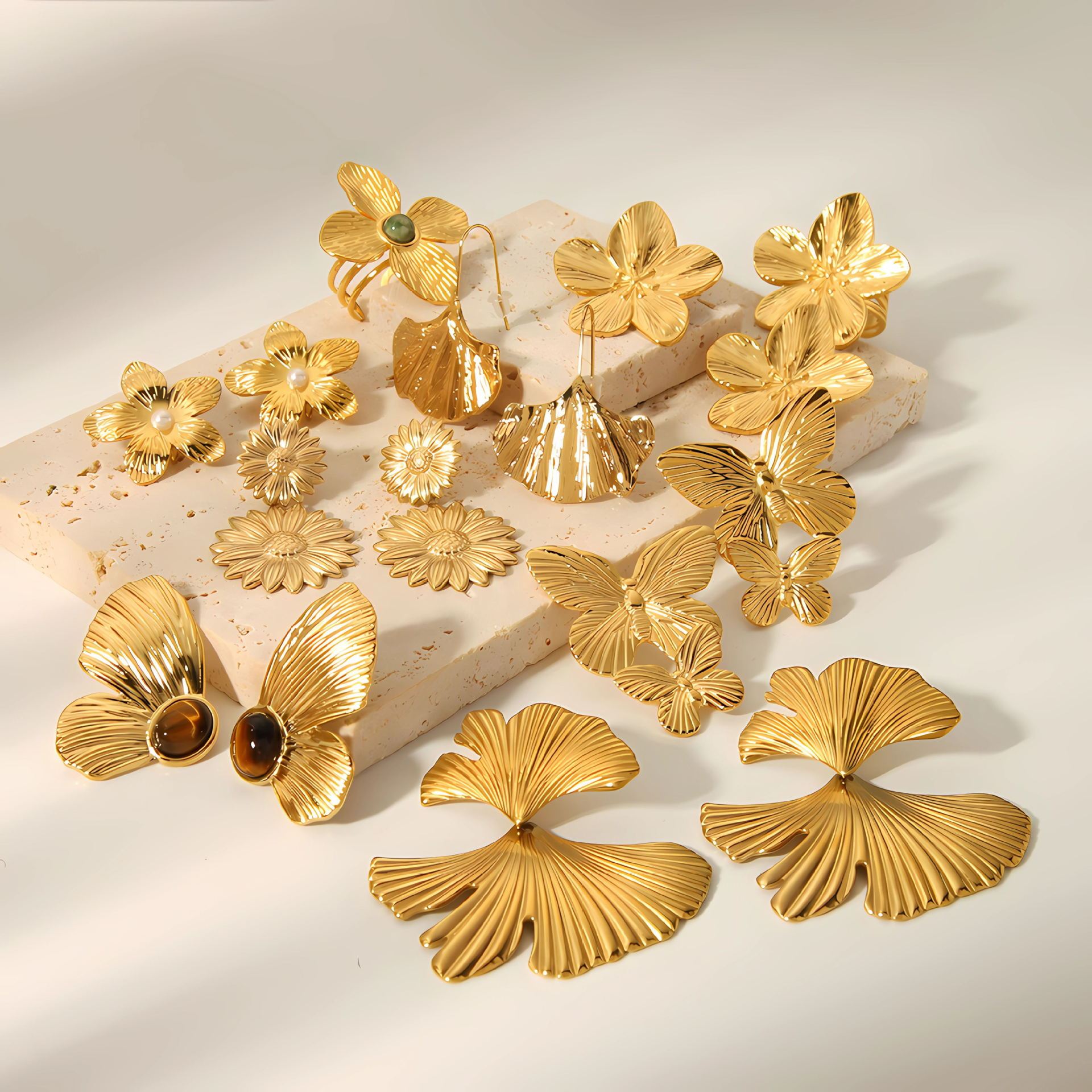 Gold floral and butterfly earrings on a light background