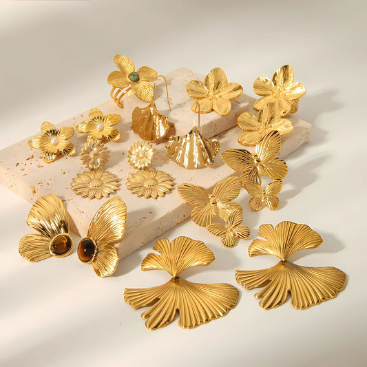 Gold floral and butterfly earrings on a light background