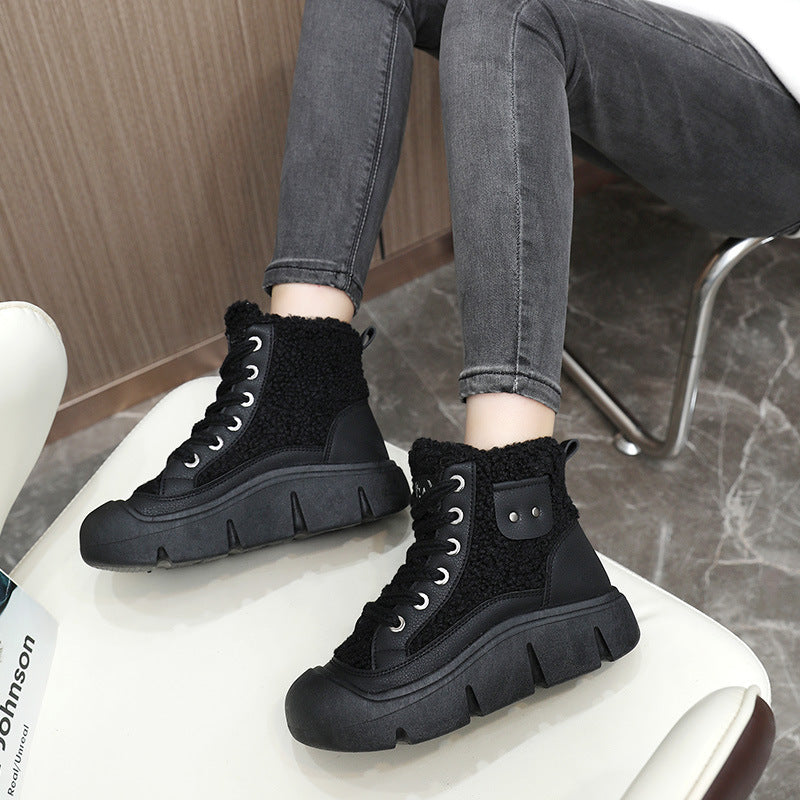 Black high-top sneakers worn with gray jeans on a white stool.