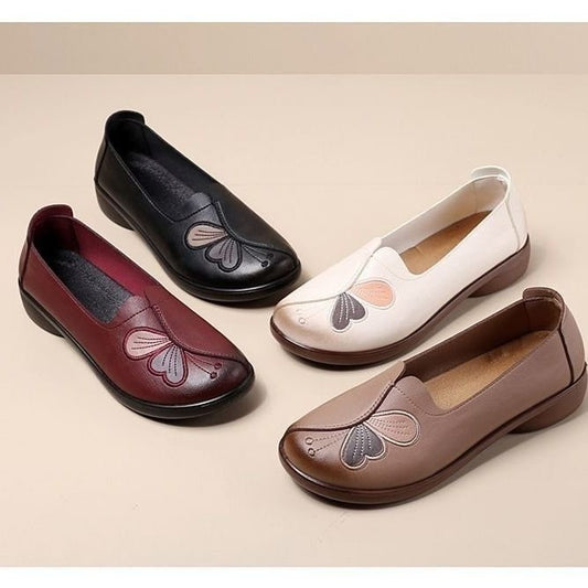 Four pairs of women's flat shoes in black, white, red, and brown on a beige background.