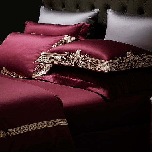 Maroon bedding set with gold embroidery on a dark background