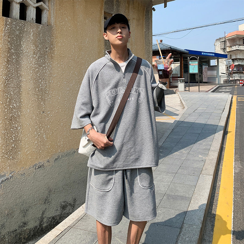 Person wearing a gray outfit with a brown bag on a sidewalk.