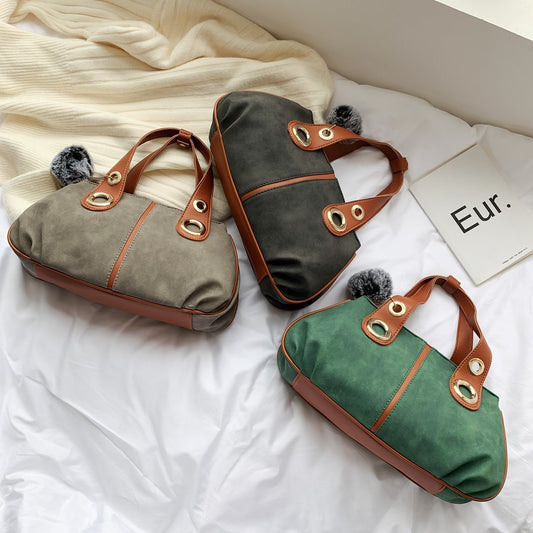 Two handbags, one gray and one green, with brown accents on a white surface.