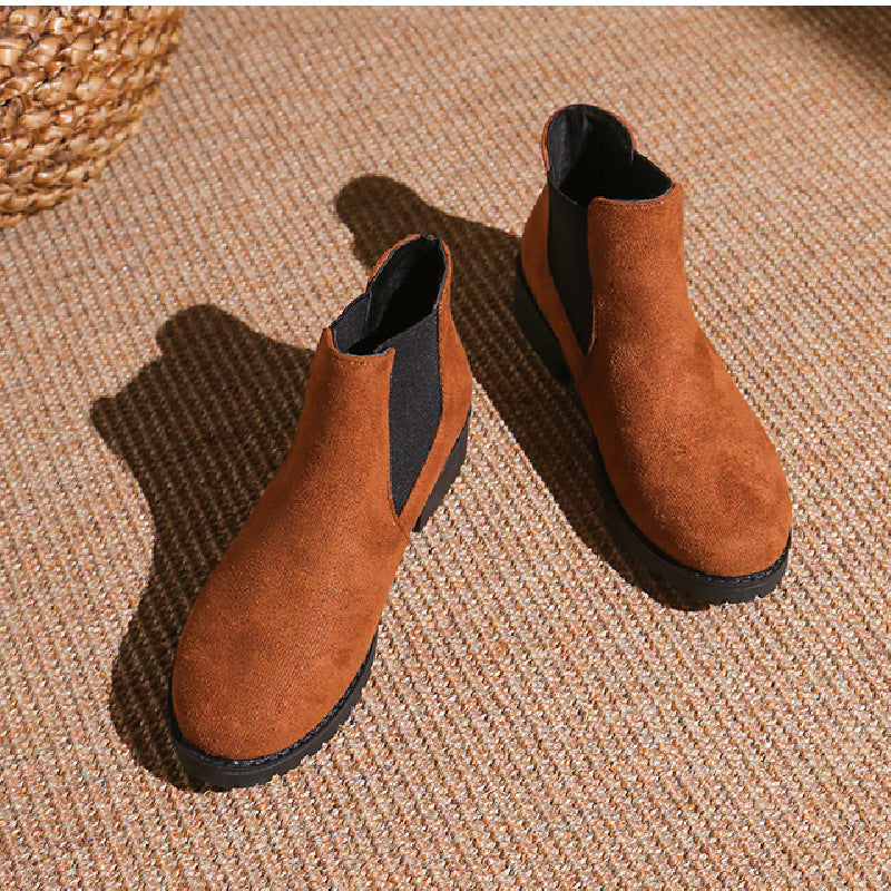 Pair of brown suede ankle boots on a textured surface