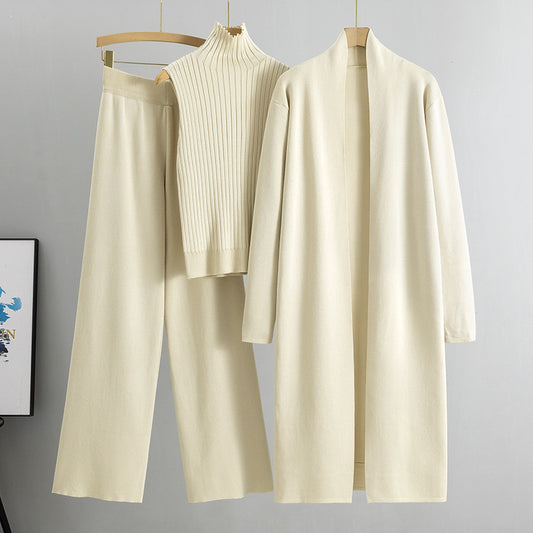 Beige outfit with a long cardigan, sweater, and pants on hangers against a gray background.