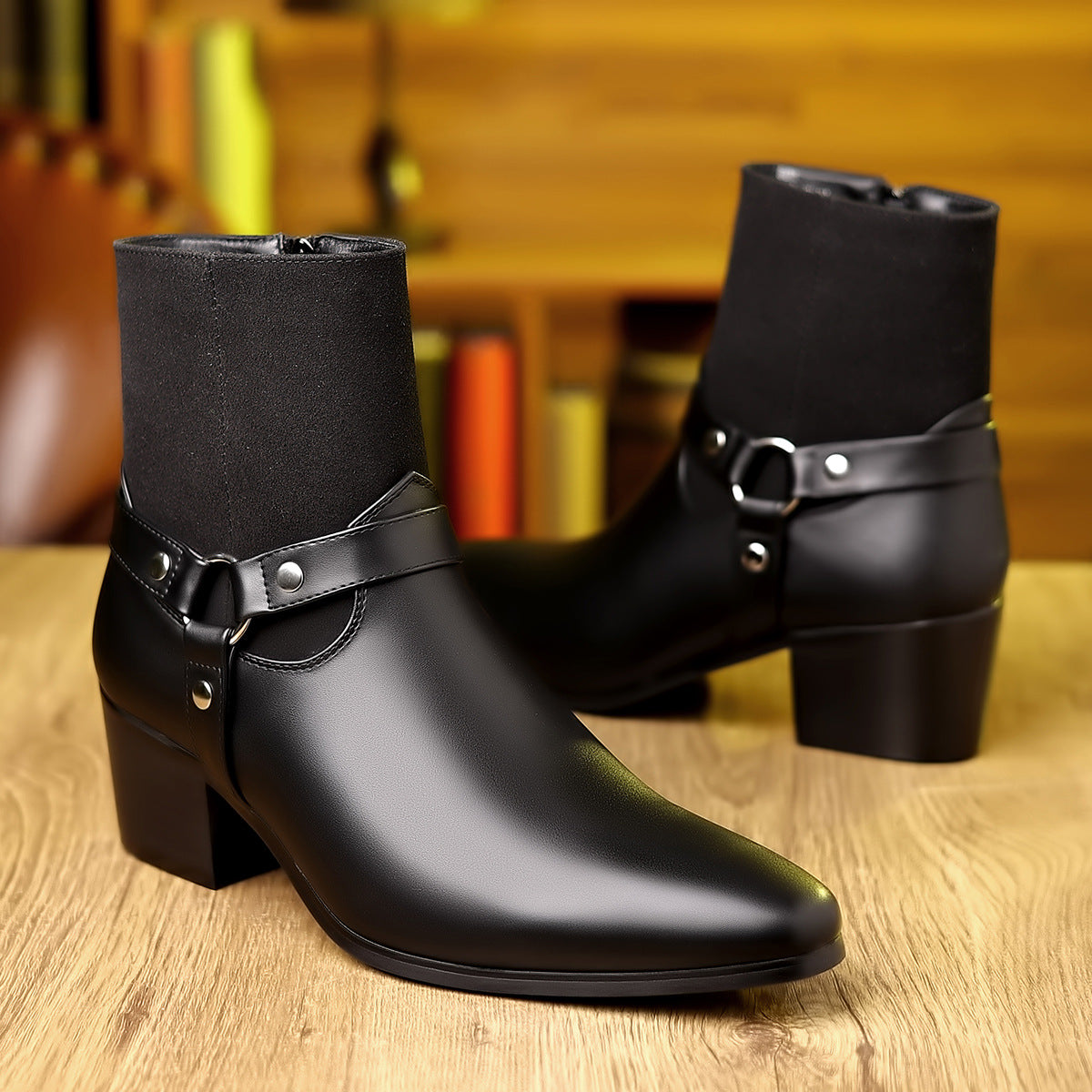 Black leather boots with buckles on a wooden surface