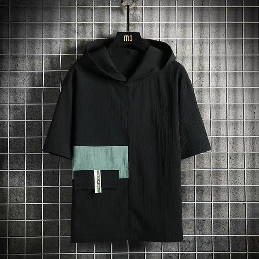 Black hooded garment with green accents on a hanger against a tiled wall.