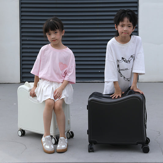 Two children with a white suitcase and a black suitcase on a gray floor.