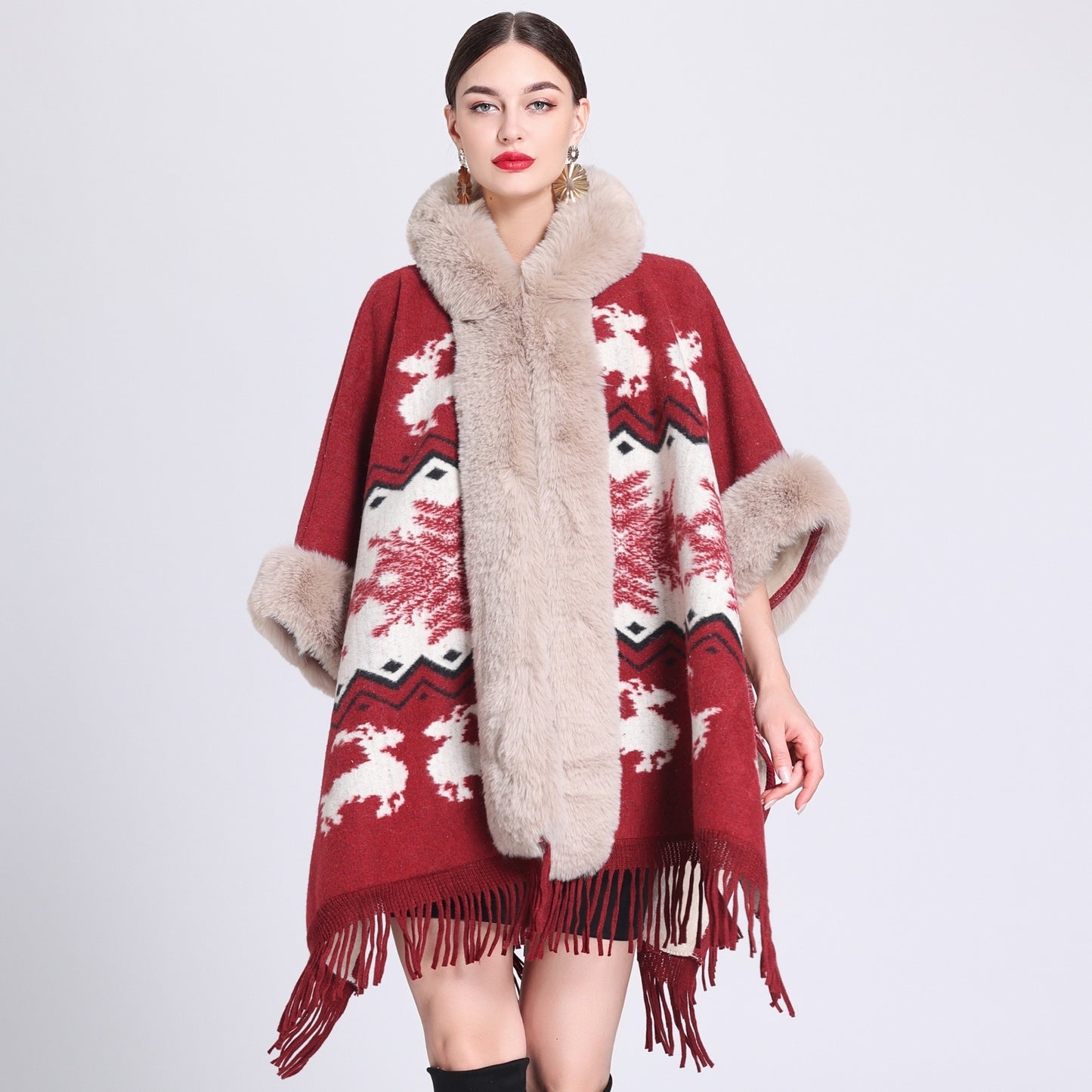 Woman wearing a red and beige patterned poncho with fur trim on a white background