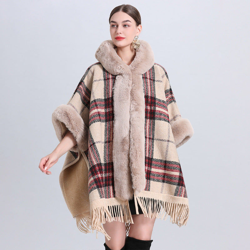 Woman wearing a plaid poncho with fur trim on a light gray background