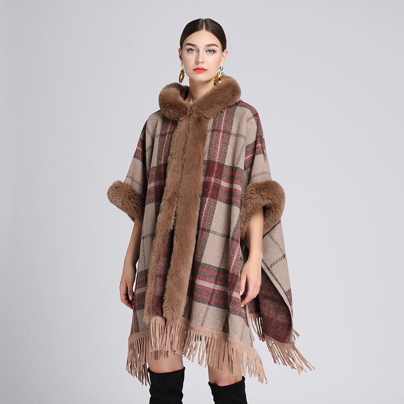 Woman wearing a plaid poncho with fur trim on a gray background