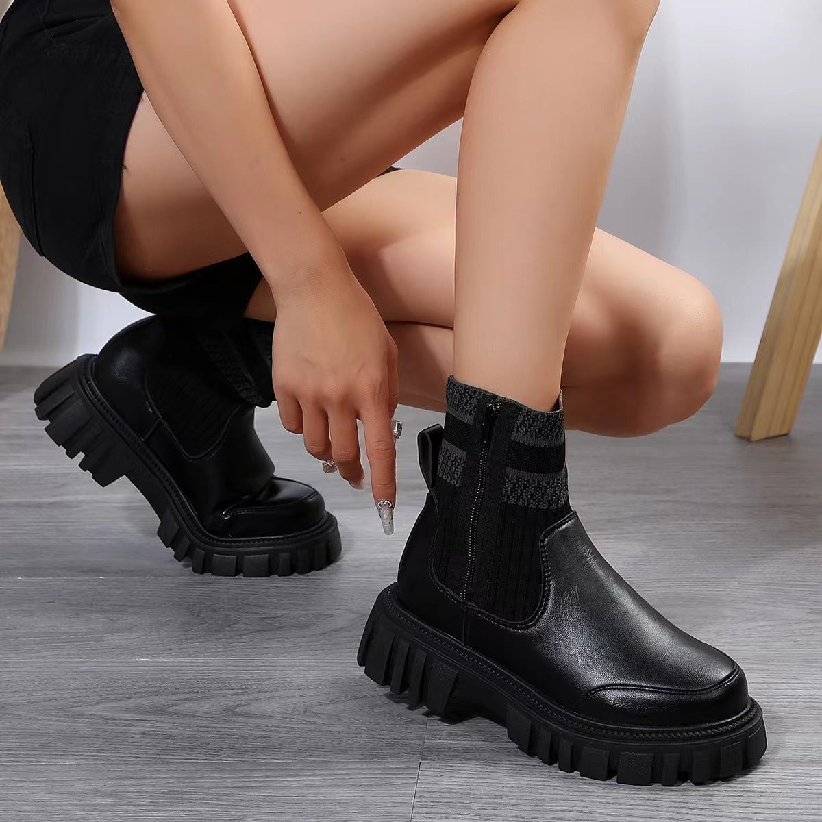 Person wearing black platform boots on a gray floor.
