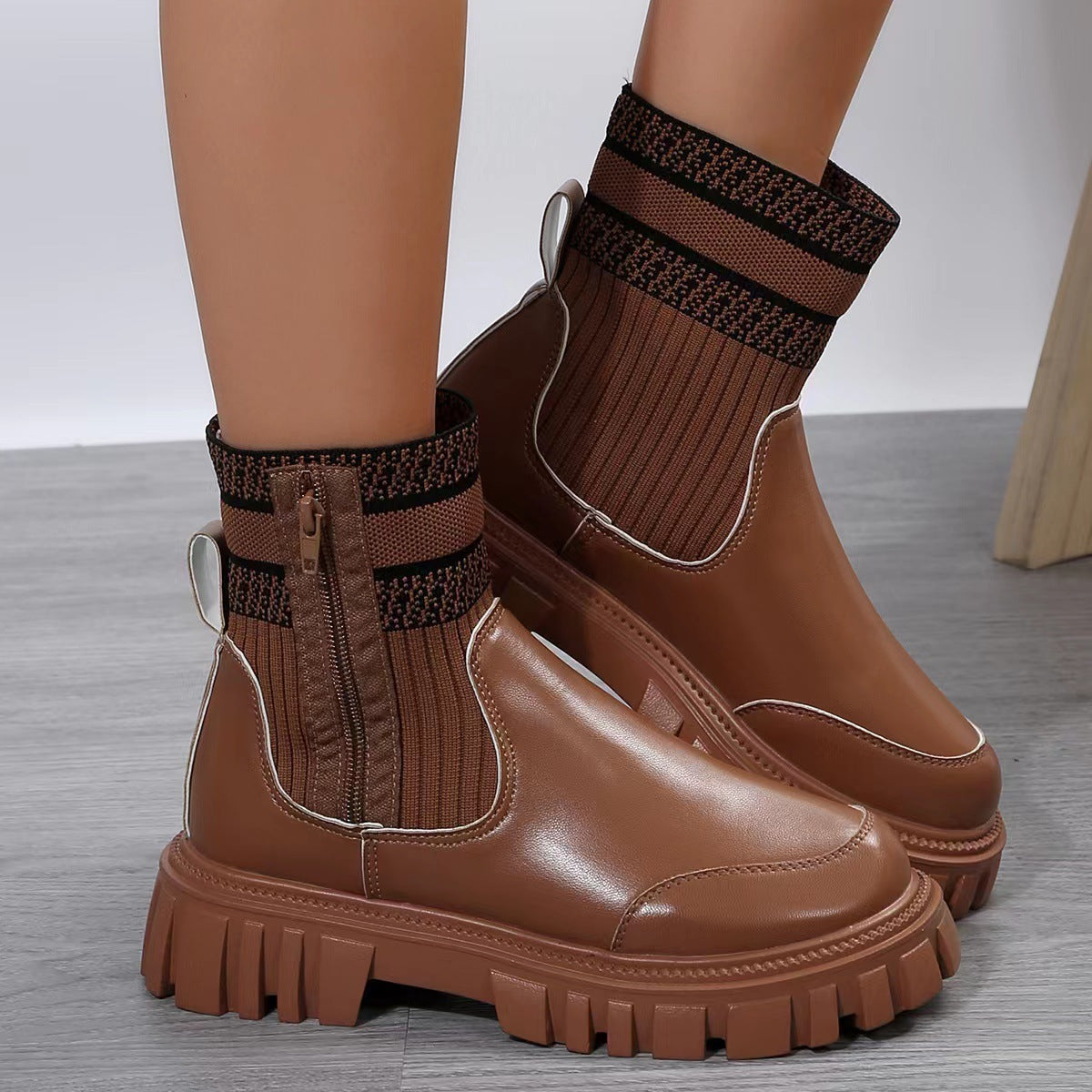 Brown ankle boots with textured soles worn with brown socks on a neutral background