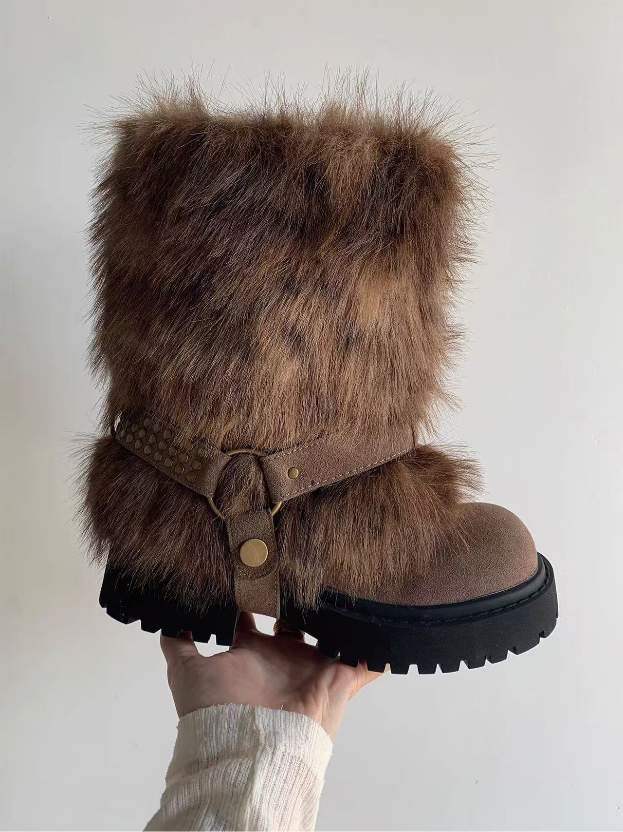 Brown fur-trimmed boot held against a white background