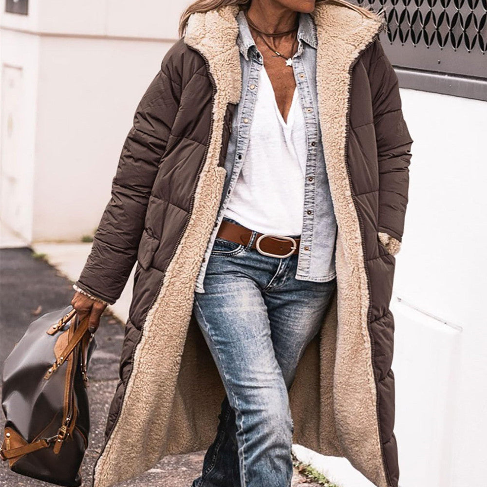 Person wearing a long brown puffer coat with beige lining, holding a gray bag.
