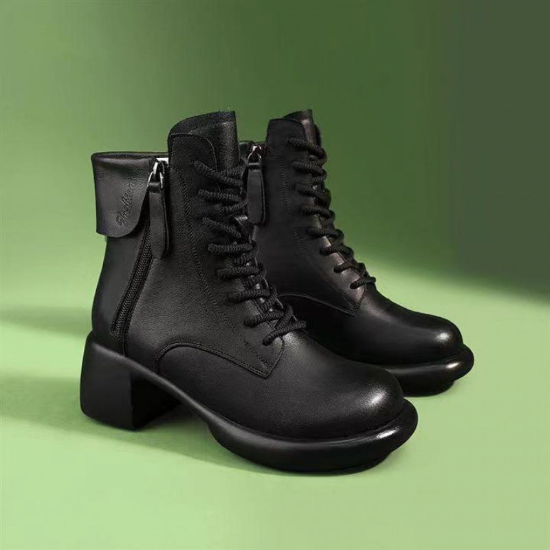 Pair of black leather boots on a green background